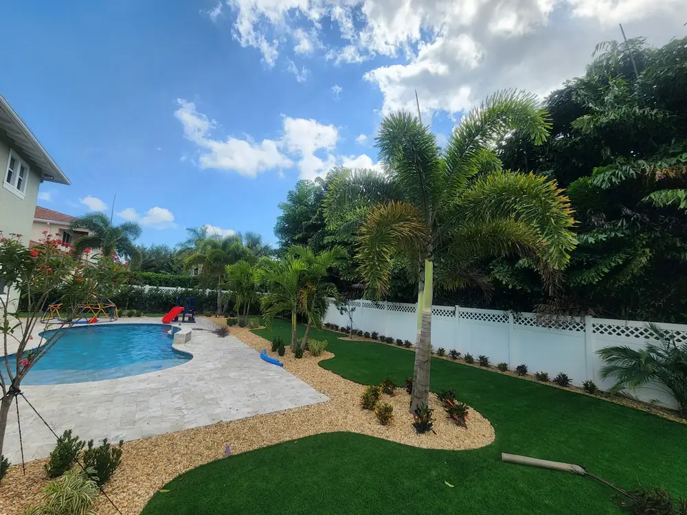 Pool with turf, rock beds and palms in a family backyard