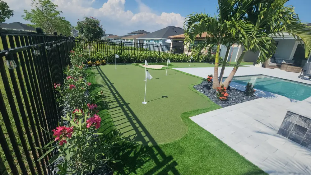Backyard putting green beside a paver pool deck